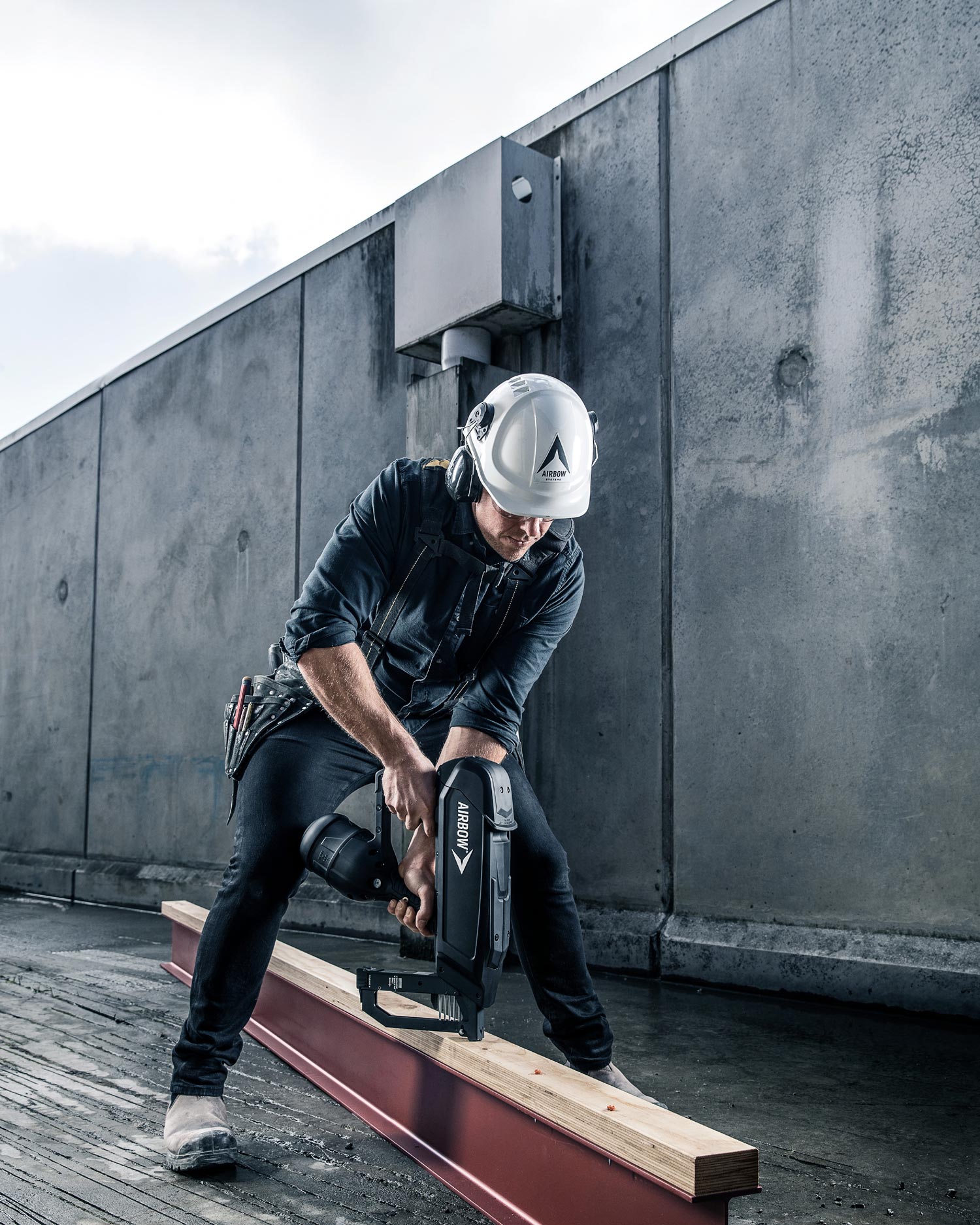 Photo of a builder using the Airbow nail gun to fire nails into a piece of wood and a steel beam