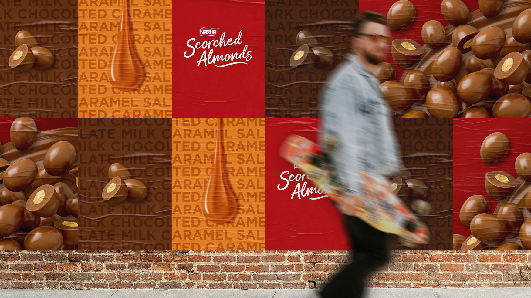 A person walks past a brick wall with outdoor posters showing the Scorched Almonds range